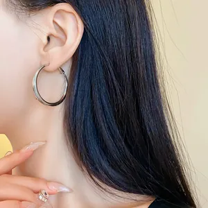 Primo piano di grandi orecchini a cerchio geometrici in argento indossati da una modella