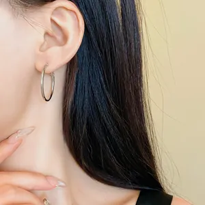 Vista ravvicinata di un orecchino a cerchio geometrico minimalista in argento su una modella
