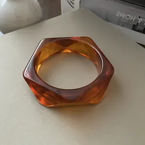 Vista detallada de un brazalete de acrílico ámbar con un moderno diseño hexagonal