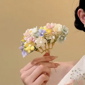 Close-up of delicate pastel fabric flower hair fork with golden metal base