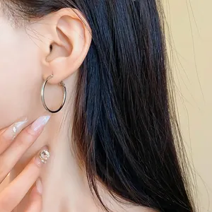 Primo piano dettagliato di un orecchino a cerchio d'argento minimalista su un modello