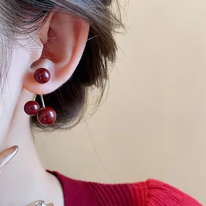 Primer plano detallado de pendientes vintage en forma de cereza rojo Ankara en una oreja