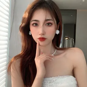 Asian model wearing elegant white acrylic flower stud earrings with pearl necklace