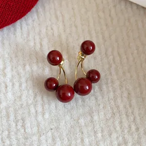 Primer plano detallado de pendientes de bola de cereza roja Ankara con diseño vintage.