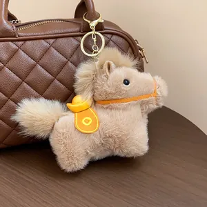 Detail shot of a cute plush horse keychain with a gold sycee saddle hanging on a handbag
