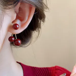 Vista detallada de elegantes pendientes de cereza rojo oscuro usados en la oreja