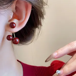 Detalle de pendientes de bola de cereza roja Ankora retro con agujas de plata