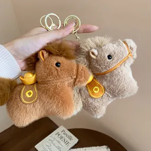 Close-up of plush horse keychains with gold ingot detail in brown and beige