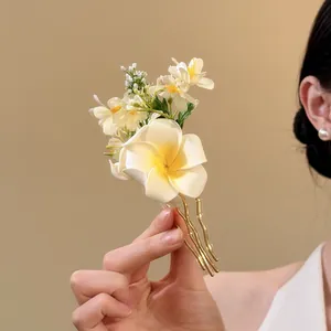 Elegant white plumeria and jasmine floral hair fork for vacation with wavy gold prongs