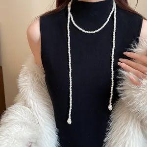 Elegant vintage-style long pearl necklace worn over a black sleeveless turtleneck