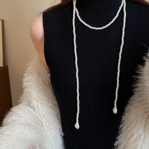 Detail of a long vintage French style pearl necklace on a black knit sweater.
