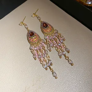 Nahaufnahme von Vintage-Quastenohrringen im Hofstil mit lila Tropfensteckern und Perlenfransen