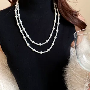 Detail view of a French retro double-strand pearl long necklace on a black turtleneck.