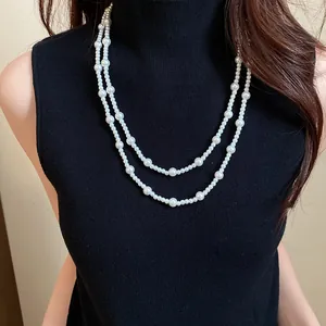 Close-up detail of a double-strand vintage pearl necklace on a black turtleneck sweater