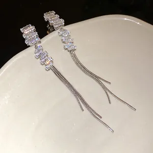 Dettaglio ravvicinato di orecchini a nappa in argento con pietre di zircone quadrate
