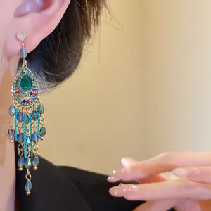 Detailaufnahme von Vintage-Ohrhängern im Hofstil mit grünem Kristall und blauen Quasten
