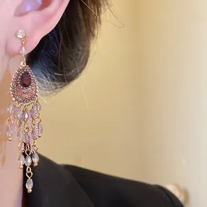 Detailansicht von goldenen Vintage-Quastenohrringen im Palaststil am Ohr des Models