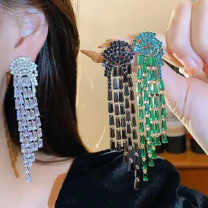 Macro detail of elegant long zircon tassel earrings in silver, black and emerald green.