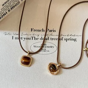 Close-up of vintage Maillard style necklaces with leather cords and gold stone pendants
