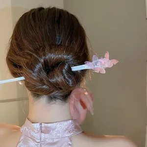 Detail view of an elegant pink acetate butterfly hair stick styled in a classic bun.