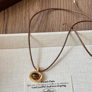 Close-up of retro Maillard style leather cord necklace with irregular oval pendant