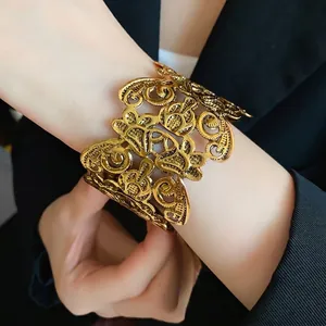 Elegante vintage gouden metalen manchetarmband met opengewerkt bloemdessin om de pols.