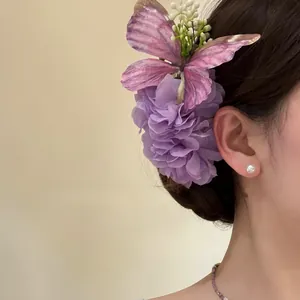 Purple fabric flower and butterfly hair clip shown on a person's hair