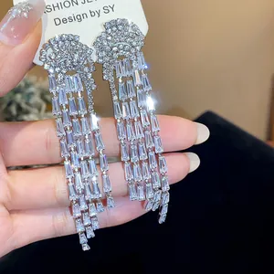Close-up detail of luxurious sparkling zircon long tassel earrings on a display card