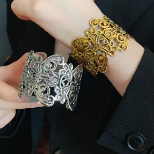 Detailopname van goud- en zilverkleurige vintage opengewerkte armbanden op de arm