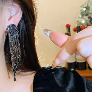 Close-up detail of luxury black zircon long tassel earrings worn by a model in festive room