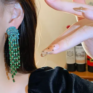 Macro detail of elegant green zircon tassel earrings worn on ear with light luxury style