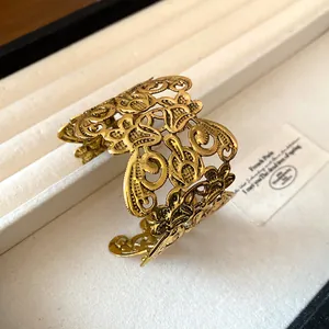 Detailopname van een vintage gouden manchetarmband met opengewerkt bloemenmotief