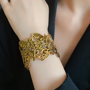 Detailopname van een goudkleurige opengewerkte armband met vintage bloemen