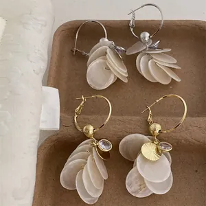 Close-up detail of elegant zircon shell tassel drop earrings in gold and silver.