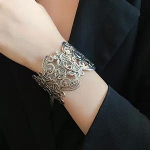 Detailweergave van een vintage zilveren opengewerkte bloemenarmband om de pols.