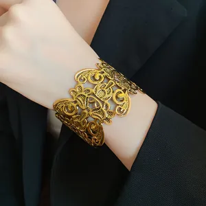 Detail van een vintage goudkleurige opengewerkte bloemenarmband op een pols
