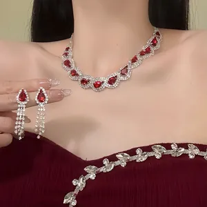 Detailed close-up view of red waterdrop gem necklace and elegant tassel earrings on a model
