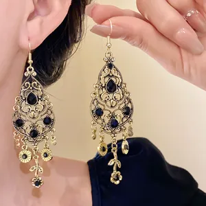Close-up of vintage gold hollow-out water drop earrings with black gemstones.