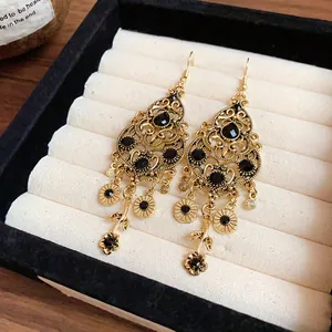 Close-up detail of vintage teardrop earrings with black rhinestones and golden tassels.