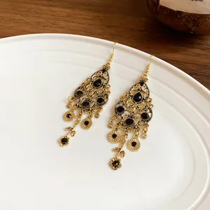 Detailed view of vintage gold teardrop earrings with elegant black rhinestones and tassels.