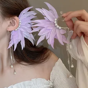Detail of purple feather ear cuffs featuring silver tassel chains and pearl accents