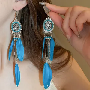 Macro view of bohemian blue feather tassel earrings featuring intricate silver mandala charms