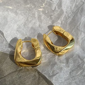 Close-up of French geometric gold-plated earrings featuring a twisted metal design