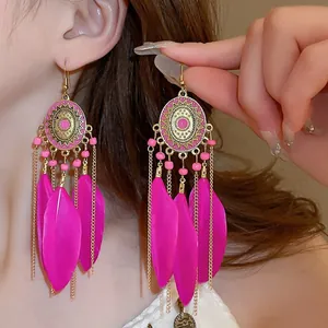 Detailed close-up of vibrant pink Bohemian feather earrings with gold ethnic tassels