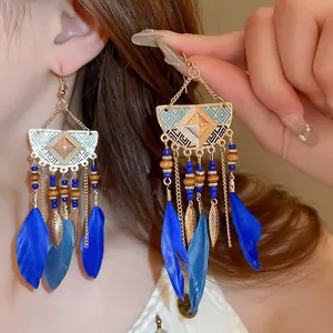 Close-up view of vintage Bohemian style feather and leaf tassel earrings on a model