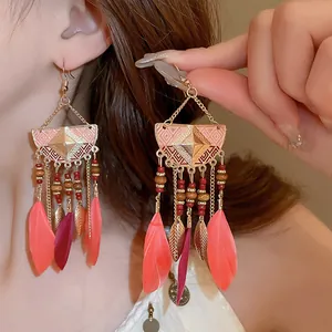 Close-up detail of Bohemian ethnic feather tassel earrings featuring leaf charms and beads