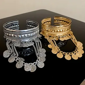 Close-up of luxury gold and silver coin tassel open arm cuffs with pyramid stud texture