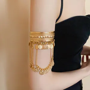 Detailed close-up of a gold arm bracelet featuring round coin pendants and chain tassels