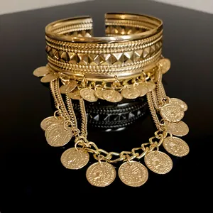 Close-up of gold coin tassel open cuff bracelet with intricate geometric patterns