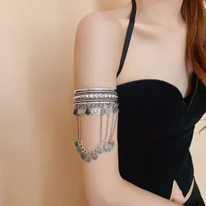 Detail showing a silver bohemian coin tassel arm cuff worn on a model's upper arm.